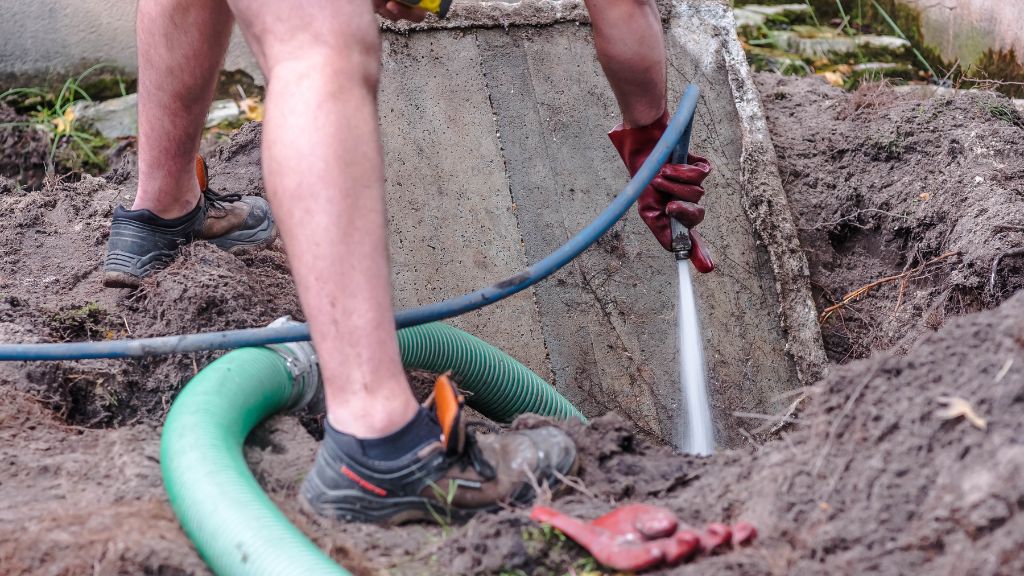 Technician cleaning septic tank with pressure washer