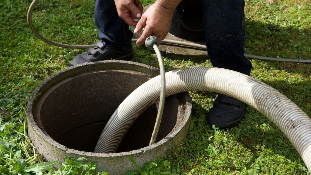 Septic maintenance technician pumping out septic tank
